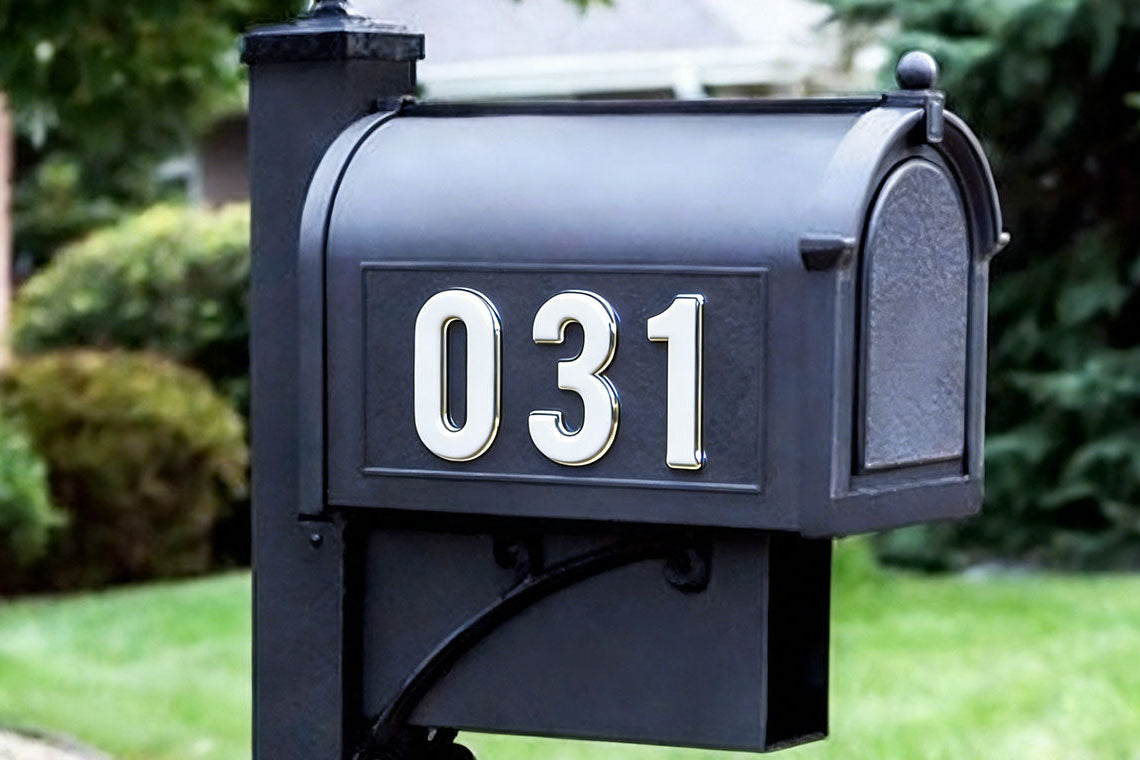 Black mailbox with white numbers '031' in a garden setting giving off a metallic luster